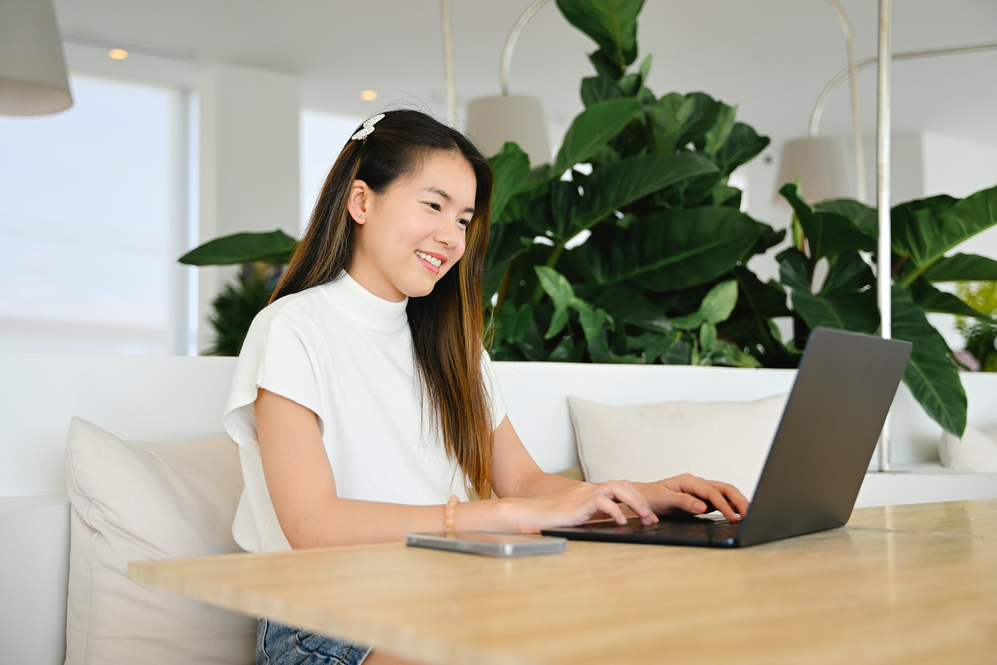 A female freelancer is working using a laptop on a working plane. The photo is of high quality.