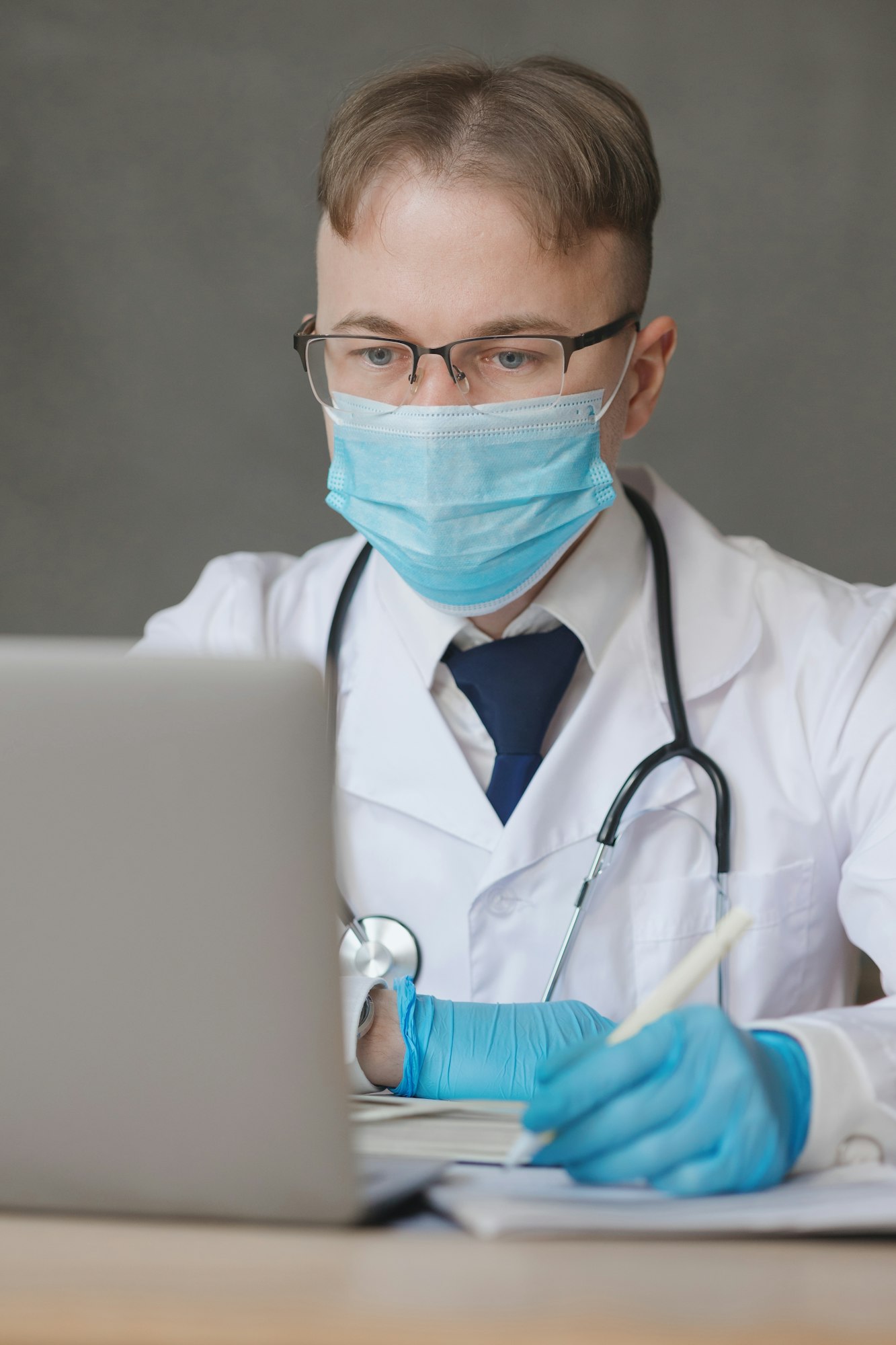 a male doctor in a medical mask and gloves watches a training webinar or conducts an online