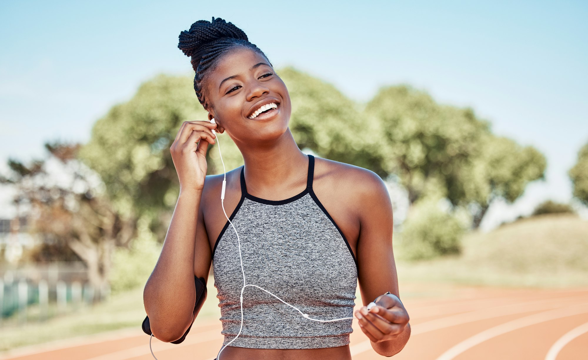 Earphones, fitness and black woman running on a track for marathon, race or competition training. S