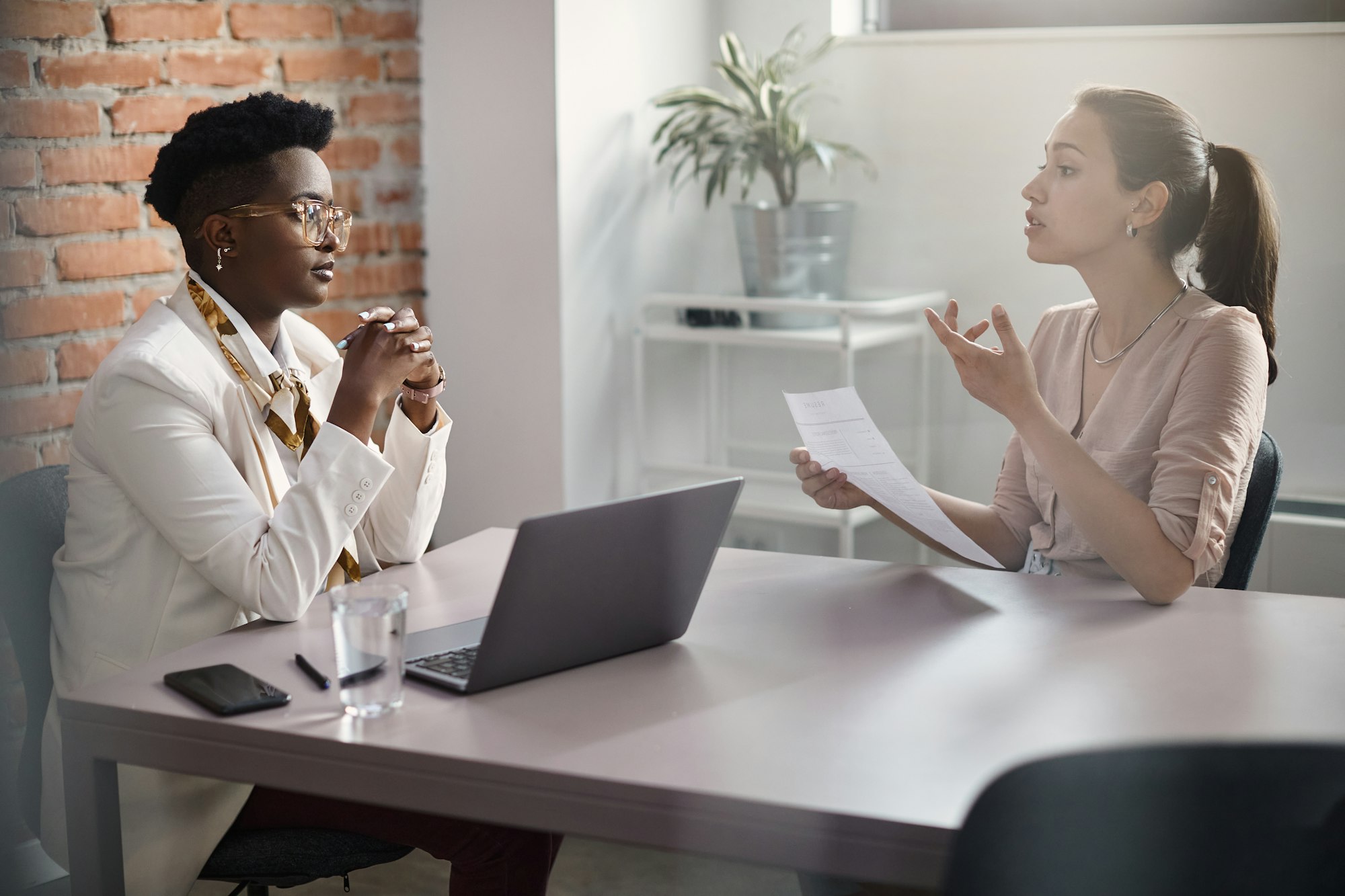 Young woman communicating with black human resource manager while applying for job in the office.