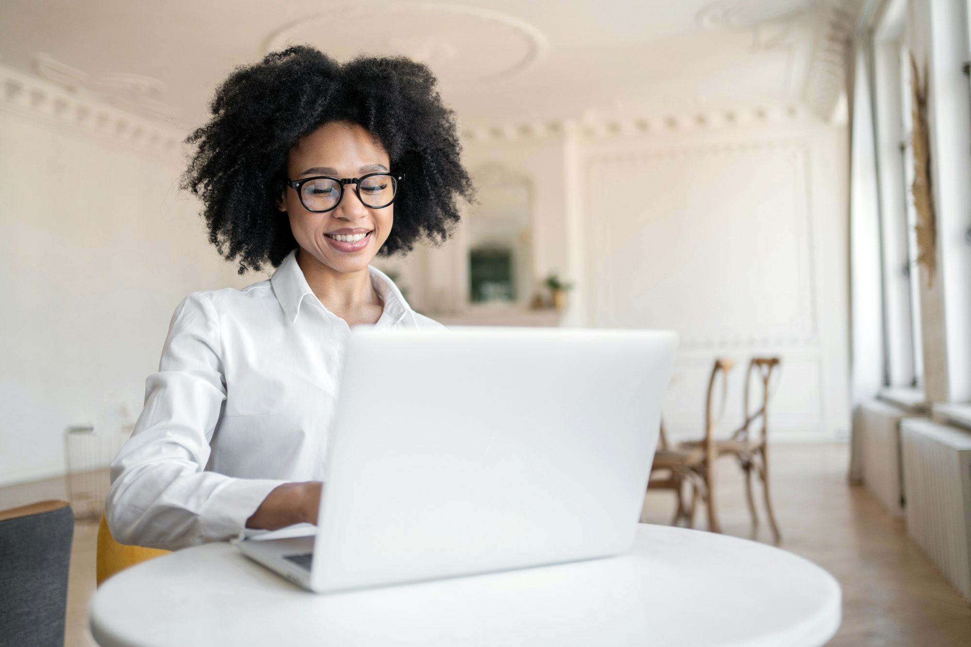 A young female student of finance courses curly training online uses a laptop computer.