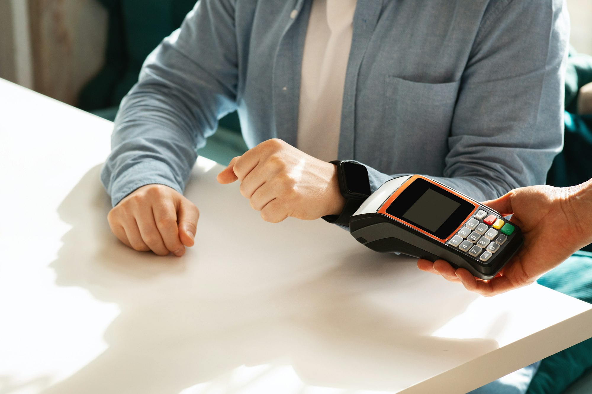 Close-up of a person's hands completing a contactless payment using a smartwatch at a point of sale